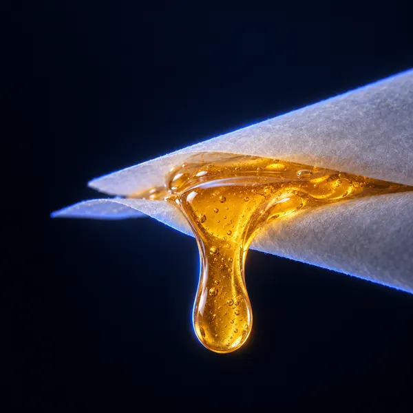 Tropfen bernsteinfarbenes Live Rosin zwischen zwei Blättern Backpapier