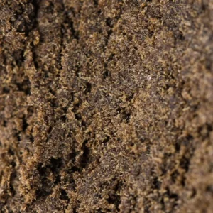 Makroaufnahme des Maroccan Hash 60% THCX, trockenes sandiges dunkelbraunes Korn