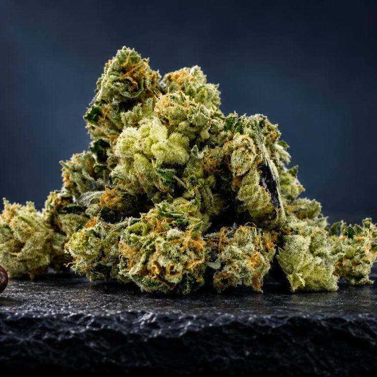Grüne, dicht strukturierte Cannabis Buds mit feinen Härchen auf dunklem Untergrund, daneben braune Samen