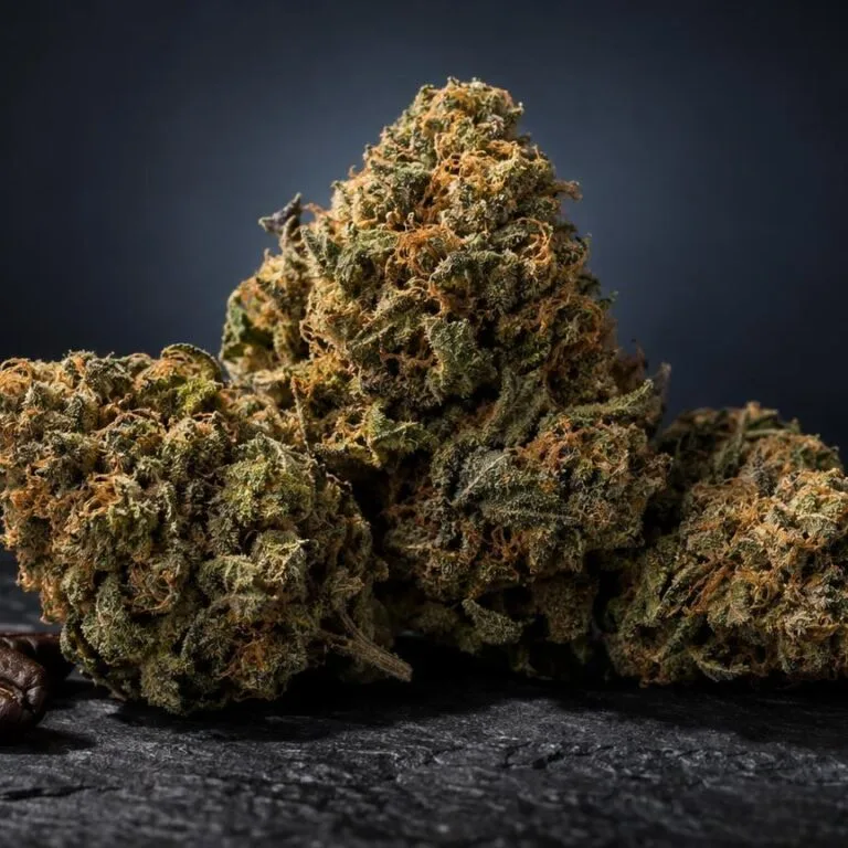 Weed AK 47 Blüten mit dichter Struktur und goldgrüner Färbung auf dunklem Untergrund, daneben Kaffeebohnen